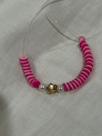 a bracelet with pink beads and a pearl on it