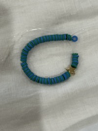 a blue and green bracelet on a white cloth