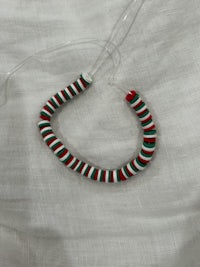 a red, white and green striped bead on a white cloth